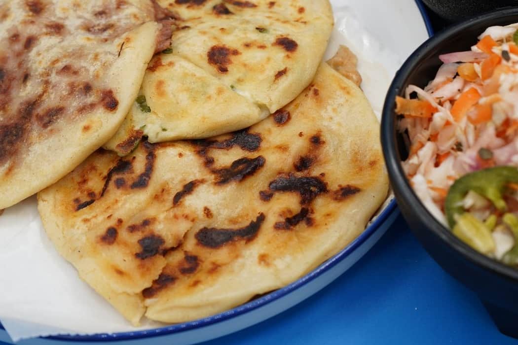 Pupusa revuelta dorada a la plancha con curtido salvadoreño en Houston TX